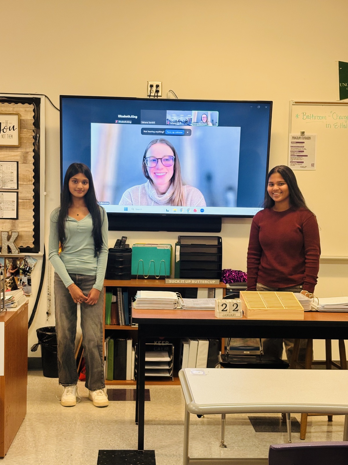 Two students with a virtual speaker on screen